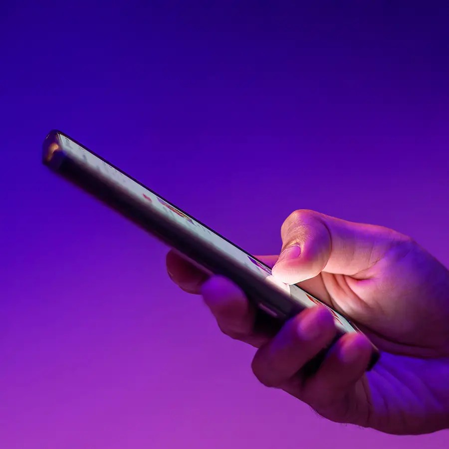 Close-up of a hand holding a smartphone, highlighting Member Experience against a purple background.