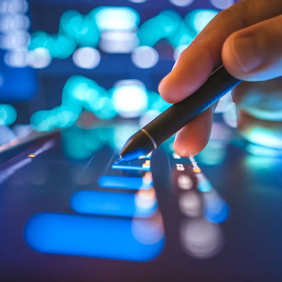 Hand holding a stylus touches a digital screen containing blue glowing charts, visualizing the concept of post-pay claims review.