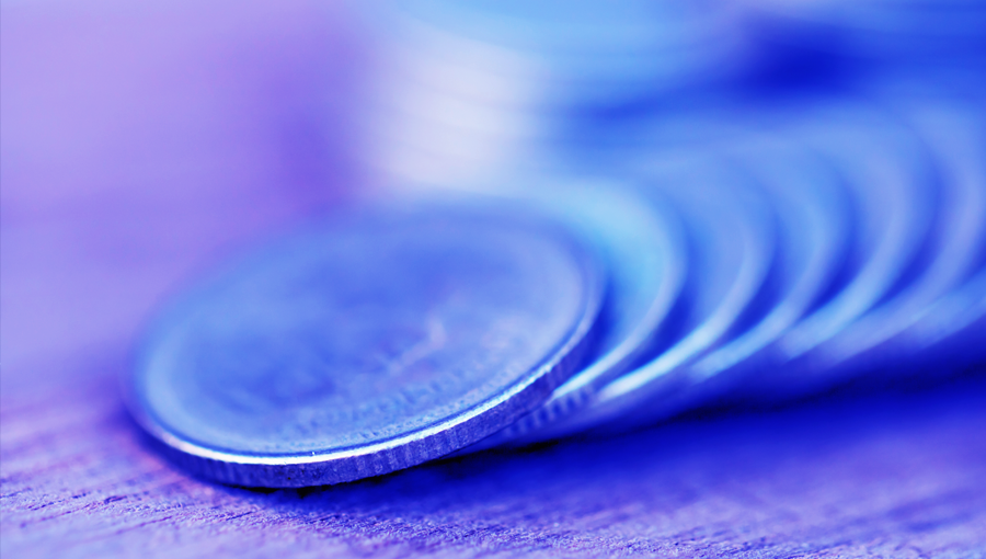 Close-up of silver coins stacked on wood, symbolizing healthcare savings with a soft blue and purple tint.
