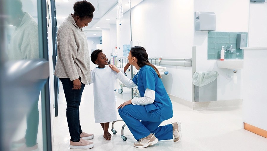 A nurse kneels, comforting a child in a hospital gown beside an adult—embracing the Four Rights of care.